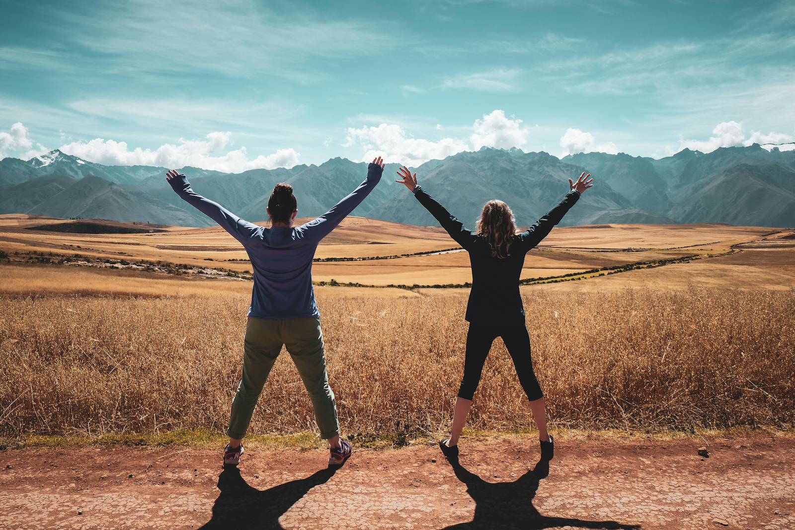 Two people embrace freedom with arms raised in the beautiful Peruvian landscape.